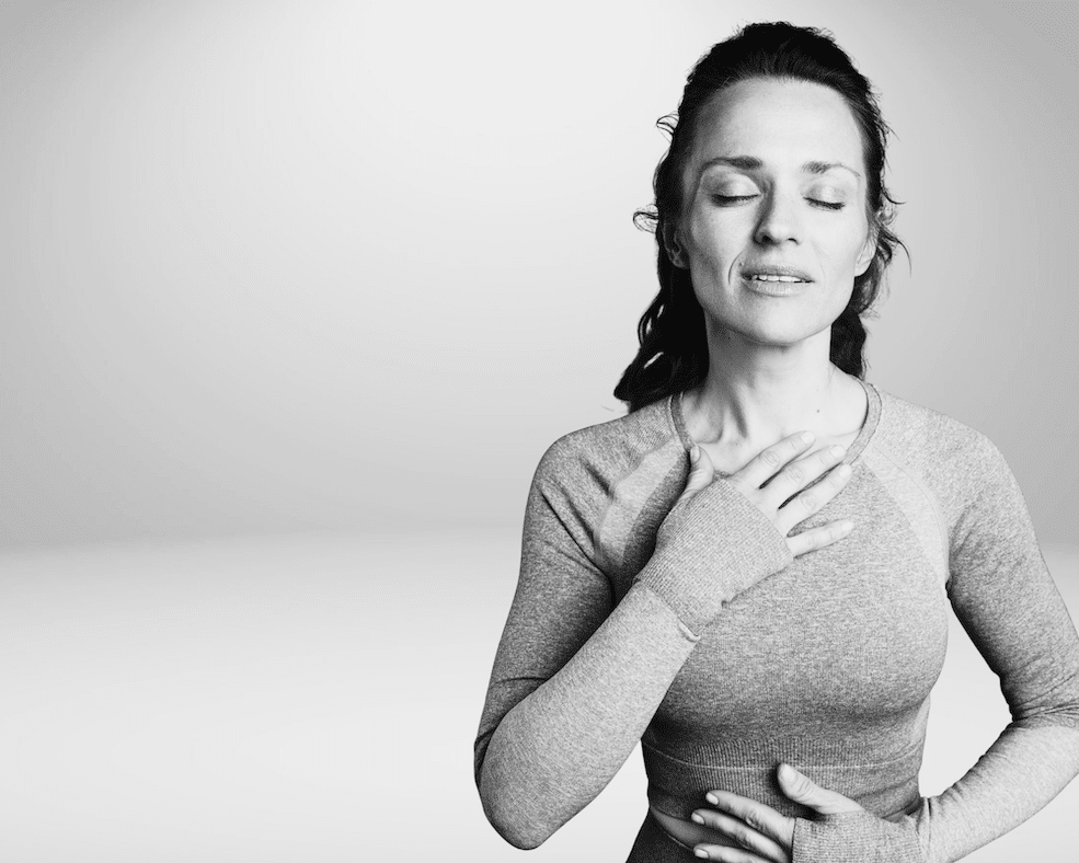 Frau mit geschlossenen Augen legt eine Hand auf den Brustraum und eine auf den Bauch – Symbol für Selbsthypnose und körperliche Beruhigung bei Reizüberflutung